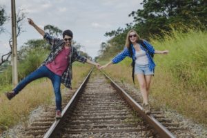 couple-holding-balance-on-train-tracks_23-2147637685